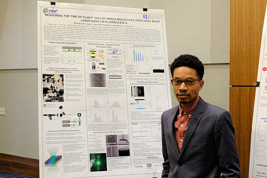 Soper group graduate student Brandon Young standing by their research poster.