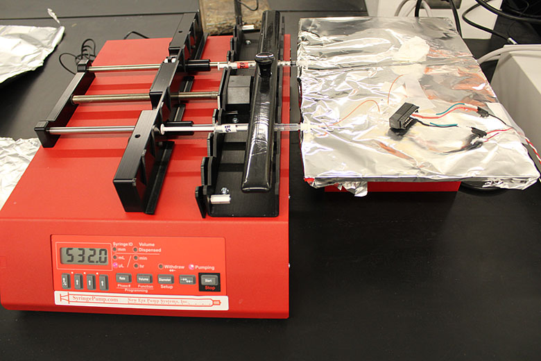 The assembled micro Coulter Counter. The syringe pump dispenses a metered amount of biological cells through the chip