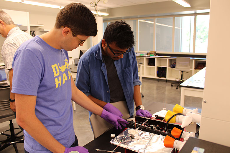 Nathan Whitman (left) and Abhik Manna (right) evaluate the setup of their micro Coulter Counter