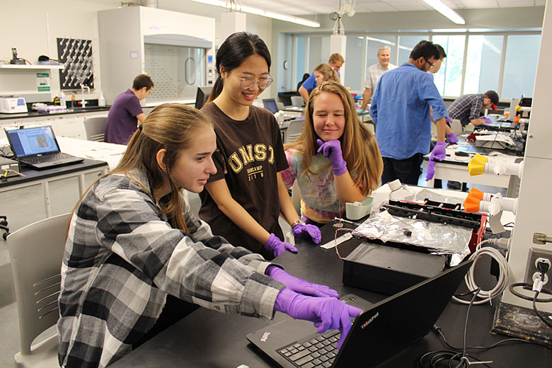 Renee Kryk, Yeonzu Son, and Mikayla Hoyle watch as cells register across their micro Coulter Counter