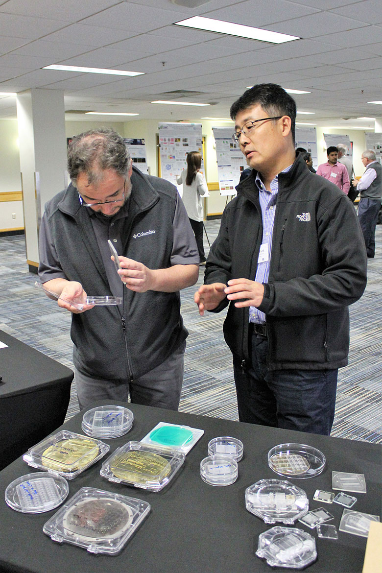 Dr. Matt Hupert (left) inspects microfluidic devices with Dr. Daniel Park (right) during the poster session