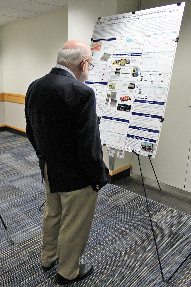 Dr. David Kaufman reads a poster on on solid phase extraction and amplification of genomic DNA
