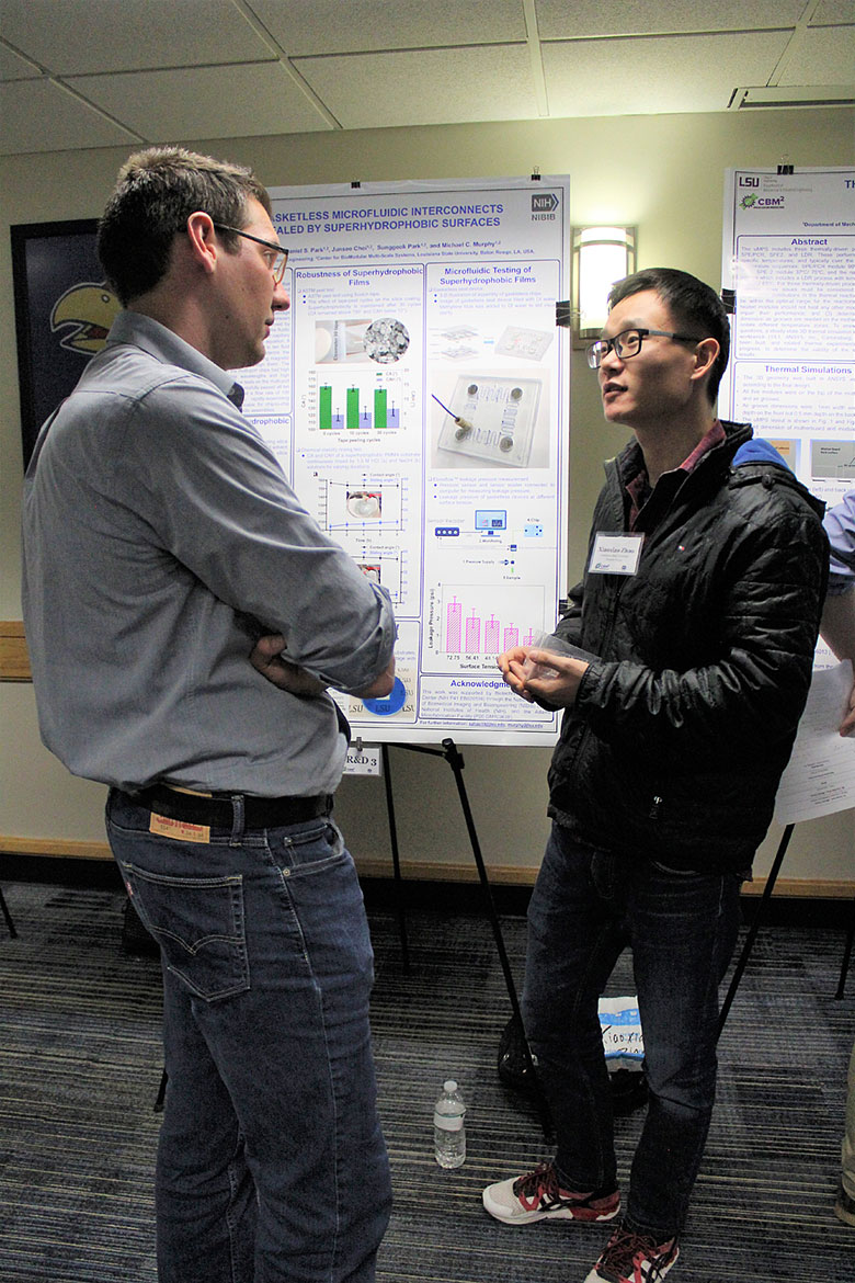 Dr. Matt Jackson (left) listens to graduate student Xiaoxiao Zhao present his poster on superhydrophobic surfaces