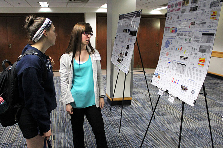 Undergraduate student Shalee Mog (left) listens to graduate student Virginia Brown (right) explain her research