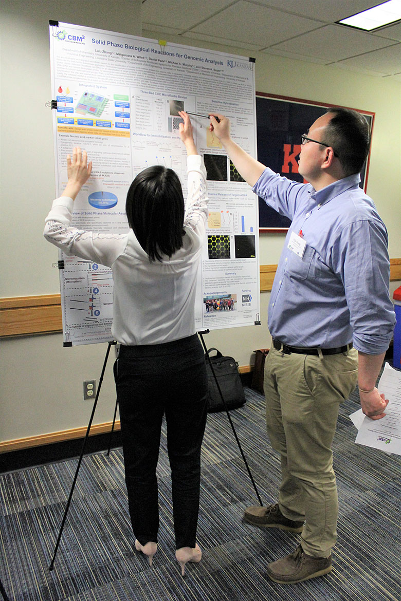 Graduate student Yijie Kang (right) and Dr. Lulu Zhang (left) discuss an image on Dr. Zhang's poster