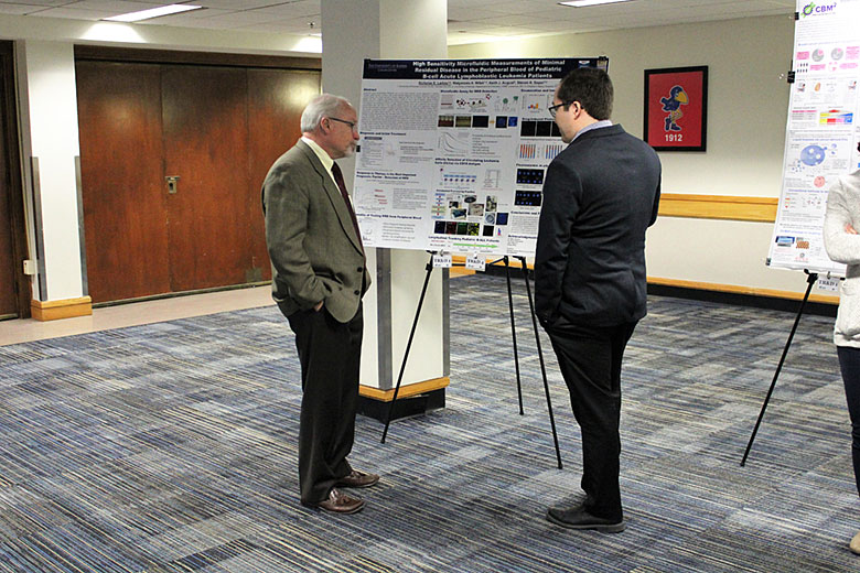 Dr. Steven Soper listens to Dr. Nicholas Larkey's poster presentation