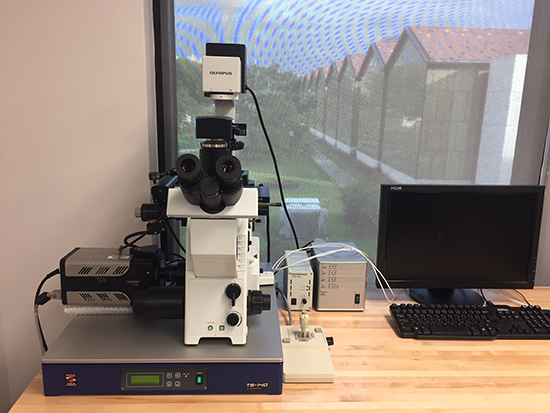 Fluorescence microscope with camera and lab equipment.