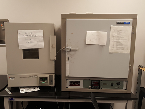 Laboratory ovens with notes attached.