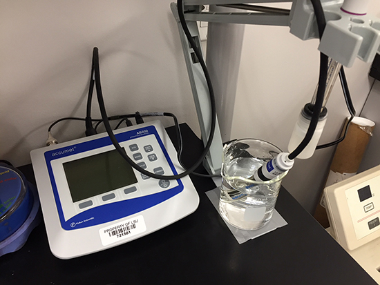  A lab setup featuring a pH and conductivity meter, with associated probes immersed in a beaker of water.
