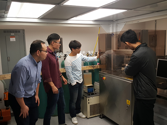 Junseo, Yijie, Xiaoxiao, and Daewon observing a NIL machine, with Daewon operating the equipment.