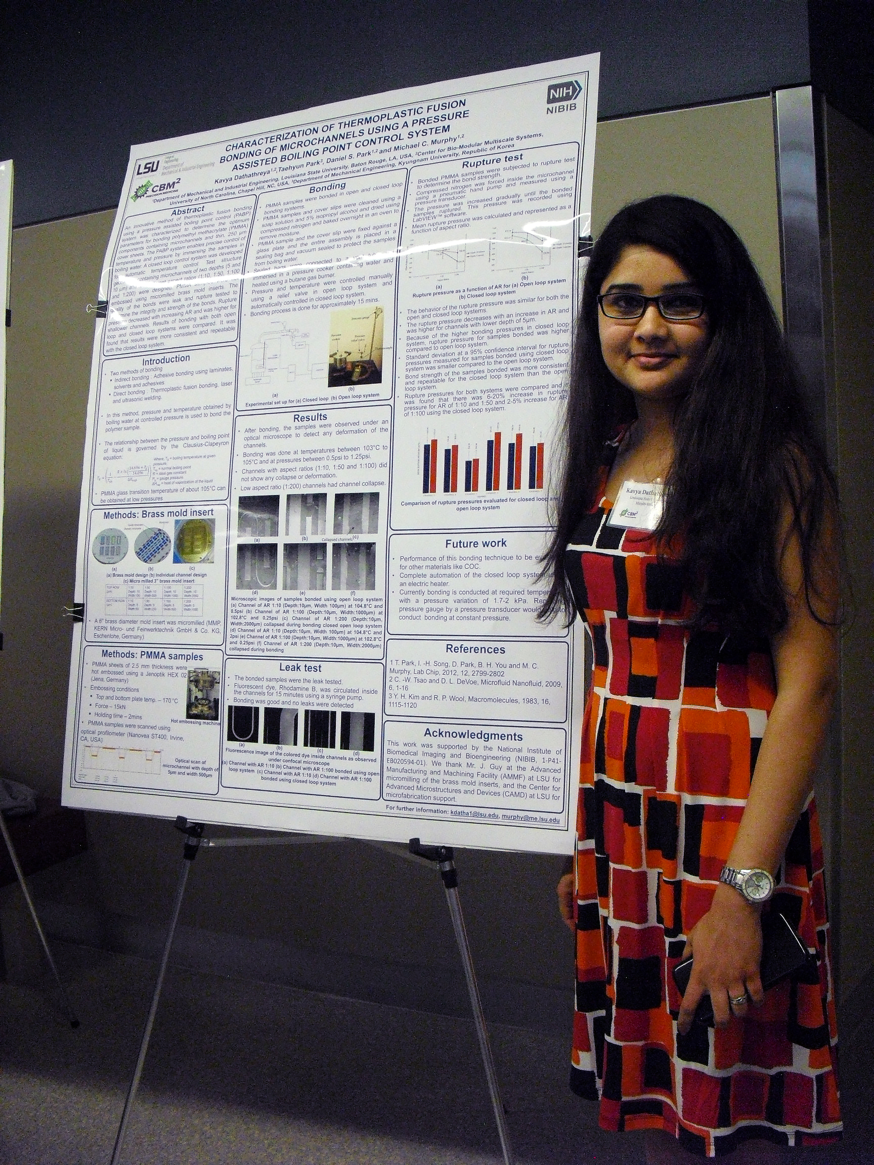 A student standing alone next to their displayed research poster.