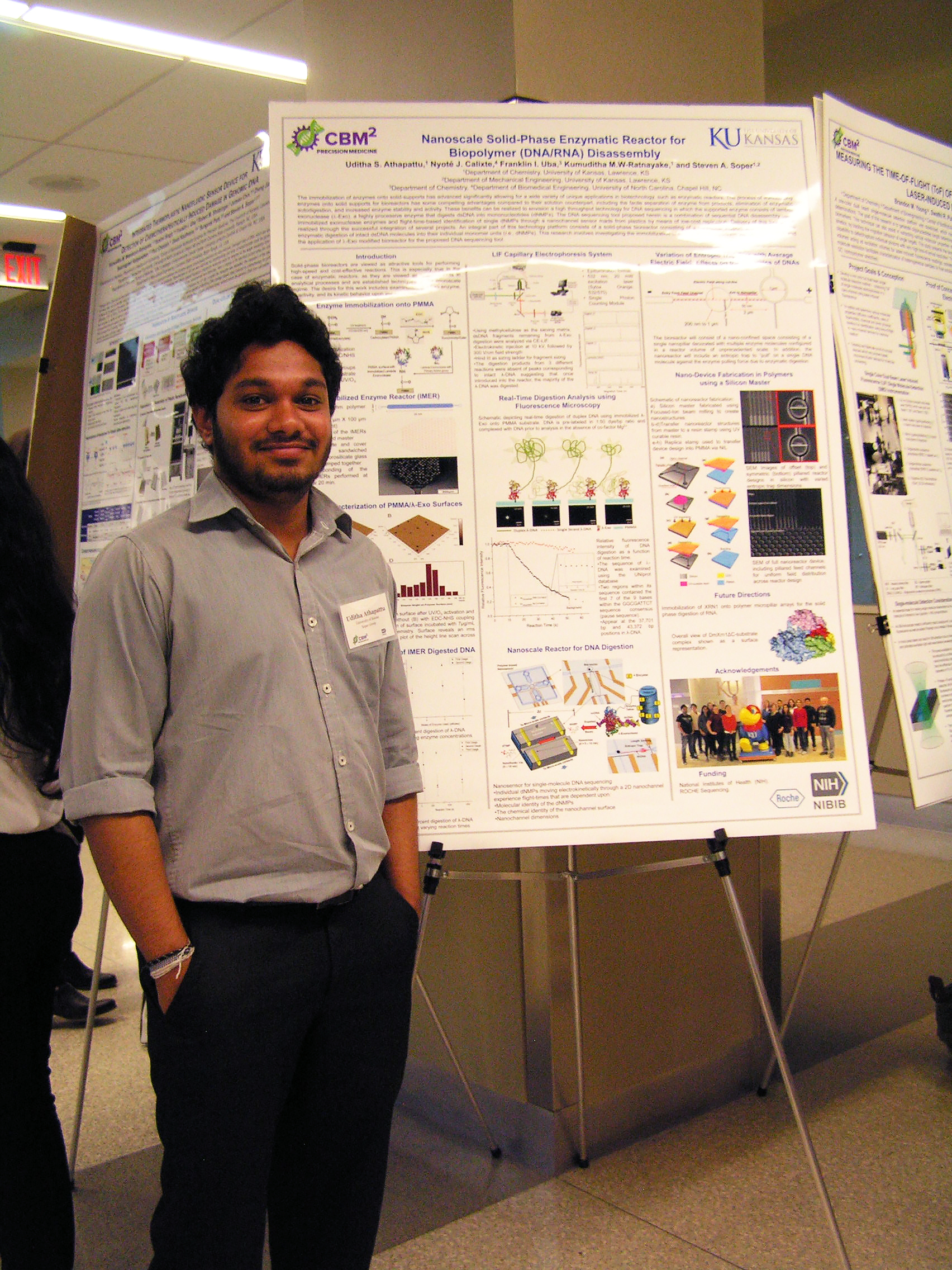 Single student positioned beside their research poster on display.