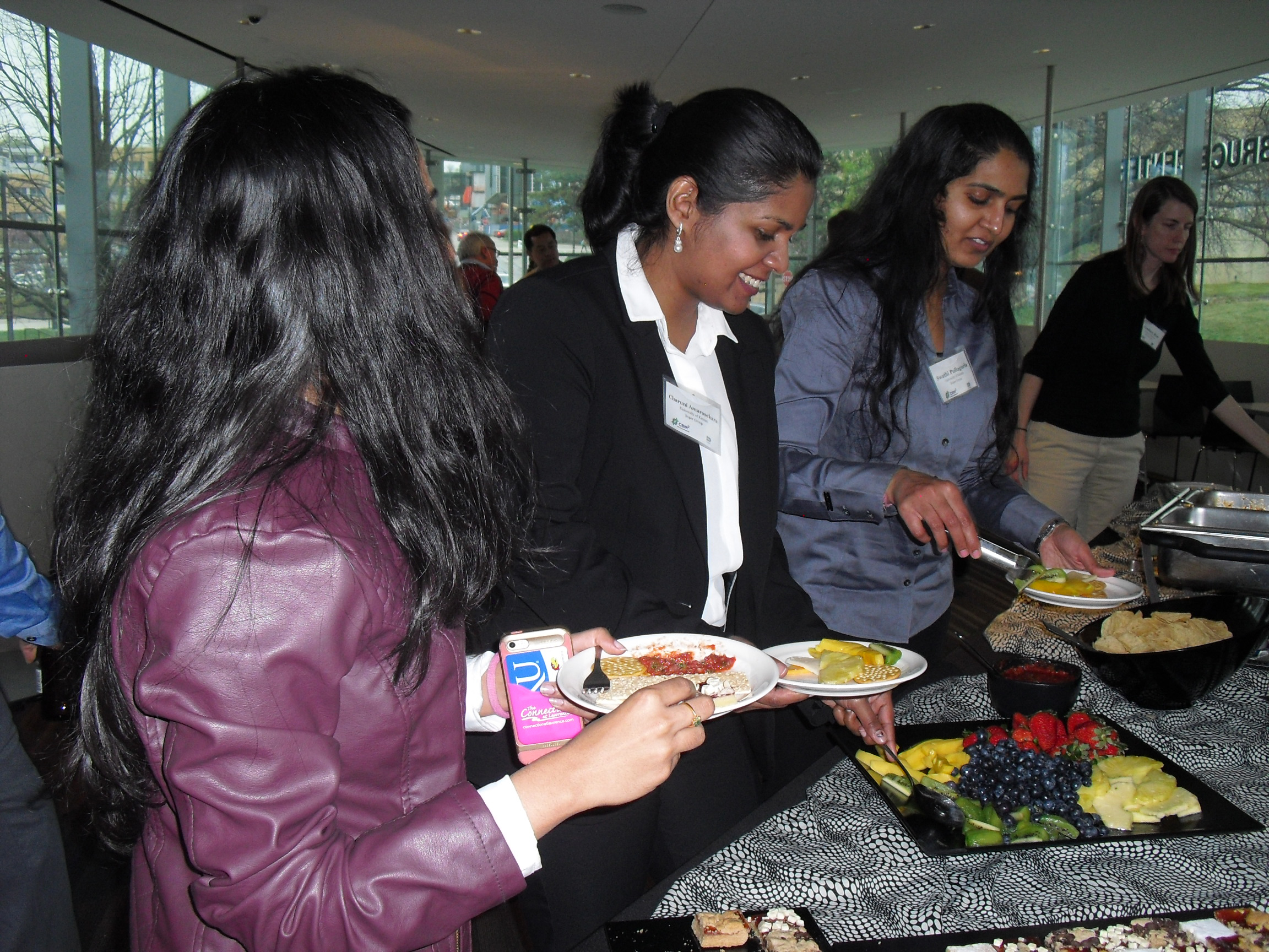 Four people standing in line to receive food at a convention service table.