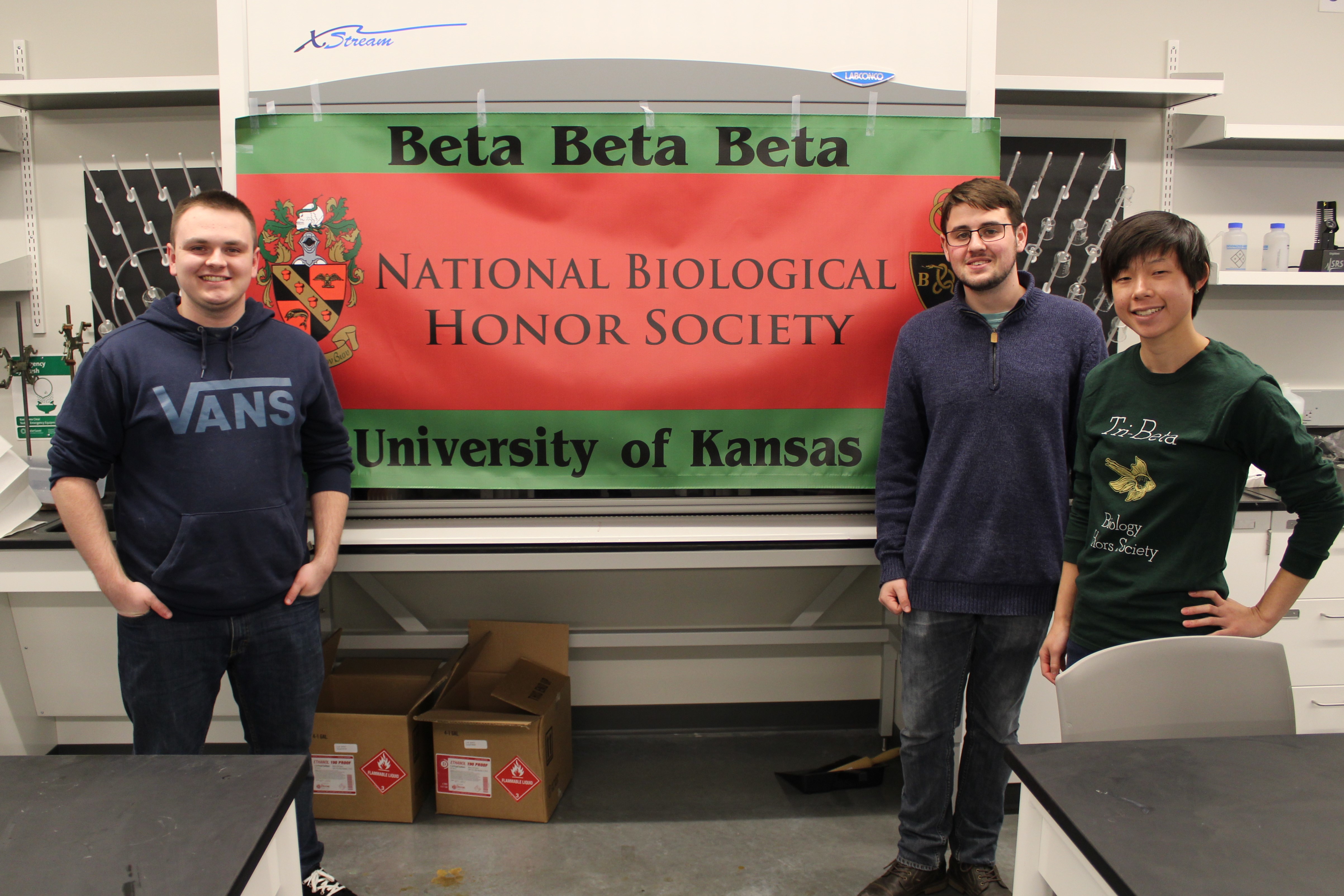 Beta Beta Beta National Biological Honor Society poster with three students standing beside it.