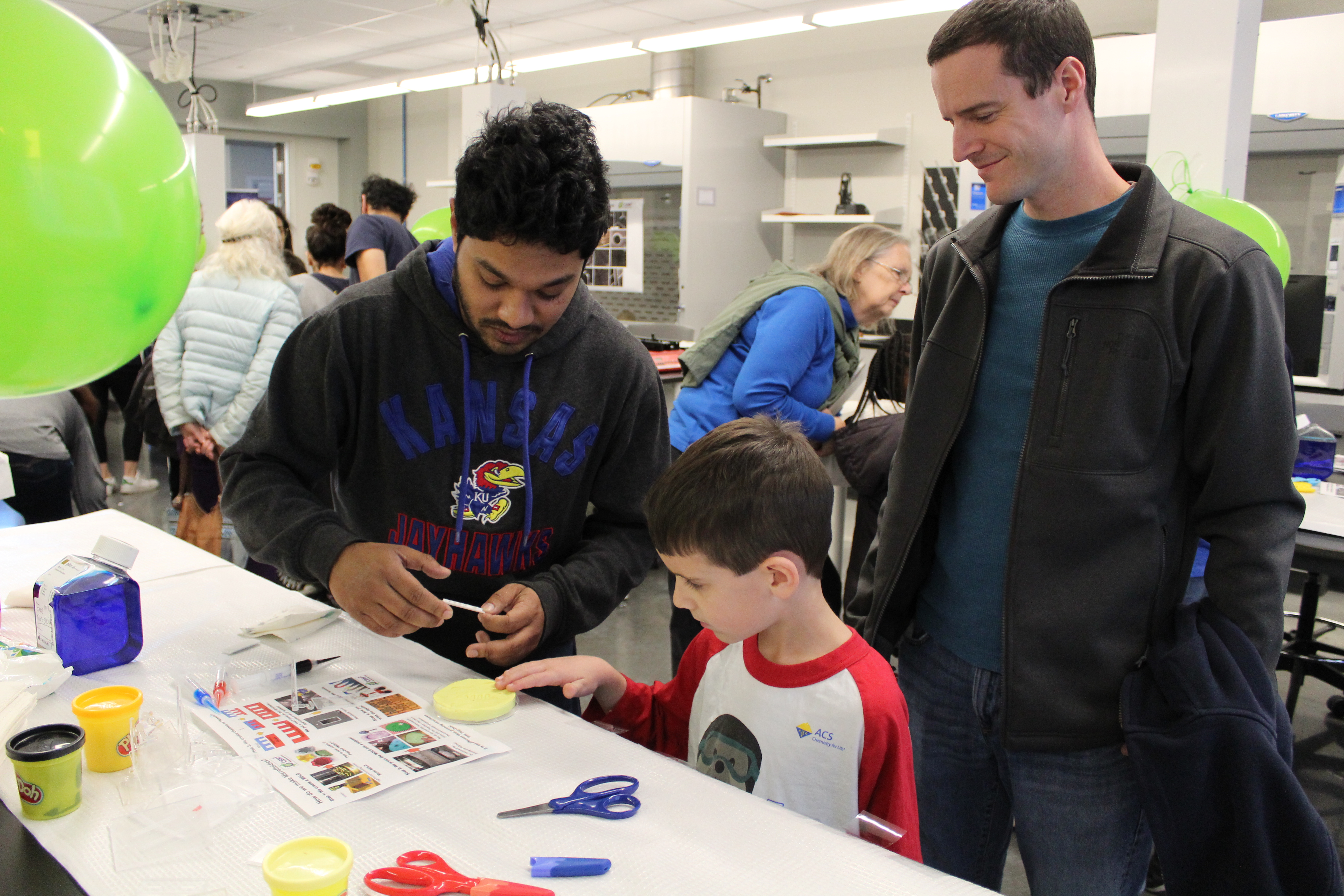 A University of Kansas student assisting a child with a craft activity.