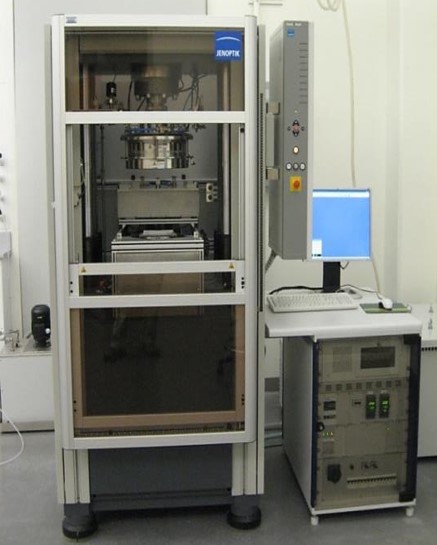 "JENOPTIK" equipment in a white frame, beside a control panel with a blue-screened monitor and grey unit, set in a lab.